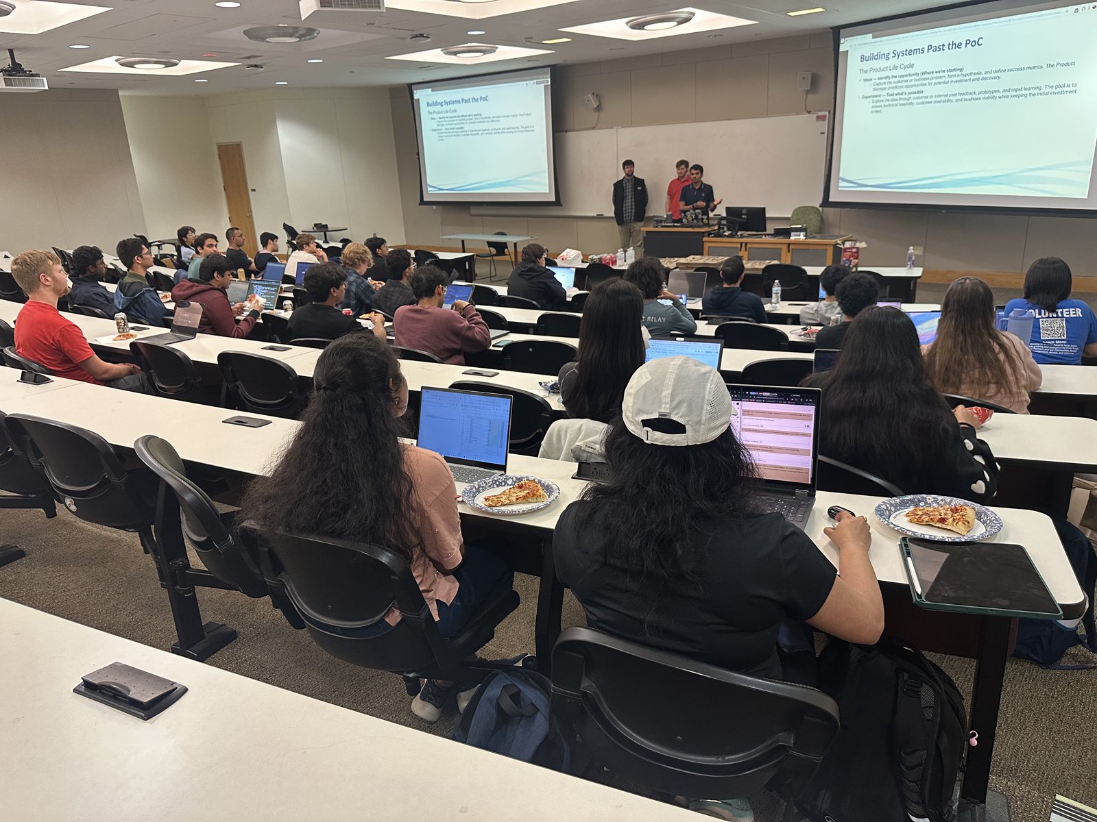 Students with laptops and pizza listening to the Direct Supply AI workshop