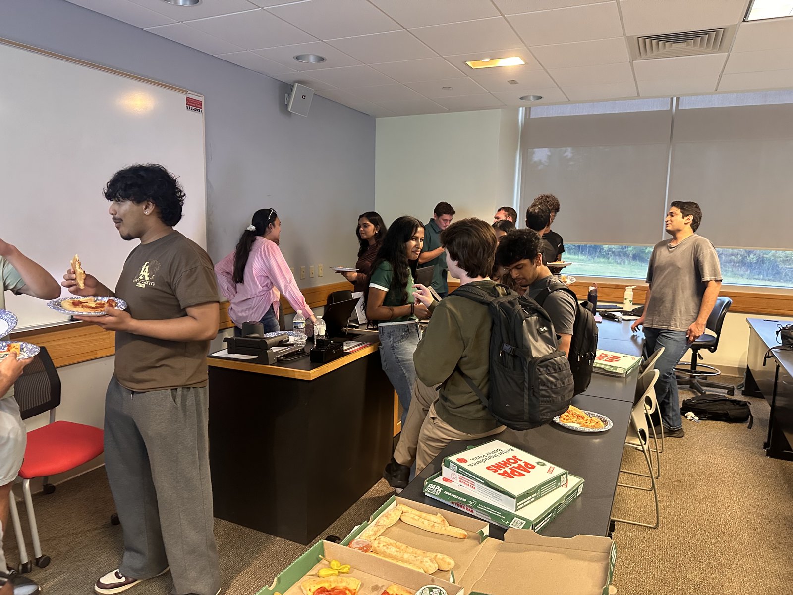 Students mingling around the pizza table at the ACM interest meeting